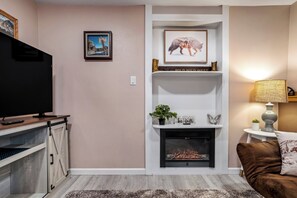 Un salon avec une cheminée, un téléviseur et un canapé.