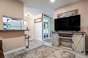 A modern kitchen with a refrigerator, a bar stool, and a countertop. - Cozy Garden Retreat | Pet Friendly w/ Private Yard (Colorado Springs)