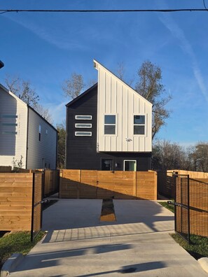 A modern two-story house with a flat roof and a wooden fence in front. - Modern 2bd 2.5ba Fully Furnished Home in North Houston (Houston)