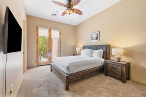 A bedroom with a bed, two bedside tables, a ceiling fan, and a door leading to an outdoor area. - Nightingale by Nest Villas | Lush La Quinta Oasis (La Quinta)
