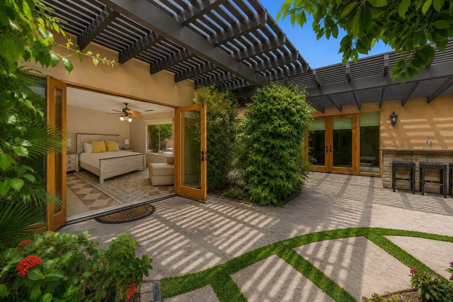 A modern outdoor patio area with a bed, a large tree, and a stone pathway.