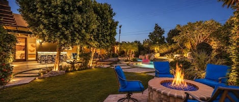 An outdoor patio area with a fire pit, seating, and a pool.
