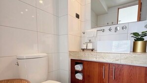 Uma casa de banho moderna com sanita, lavatório e espelho.