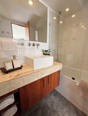 A modern bathroom with a large mirror, a white sink, and a glass-enclosed shower. - Apartment in Providencia near the Costanera Mall (Providencia)