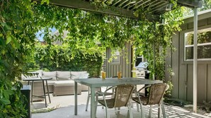 Una veranda esterna con tavolo e sedie, un divano e un barbecue.