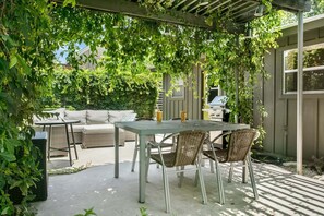 An outdoor patio with a table and chairs, a sofa, and a grill. - The Nest | Charming 2BR Fredericksburg home with grill, full kitchen, and washer/dryer (Fredericksburg)
