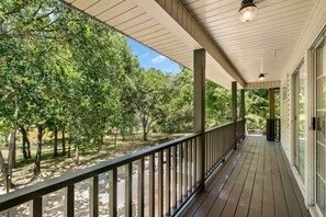 A covered porch with a view of trees and a clear sky.