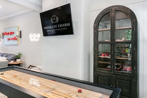 Ein Billardtisch in einem Raum mit einem Schild für 'Absolute Charms Luxury Accommodations' und einer großen, bogenförmigen Glasschranke.