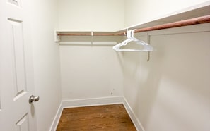 Una esquina de una habitación con piso de madera, una puerta blanca y una pared blanca.