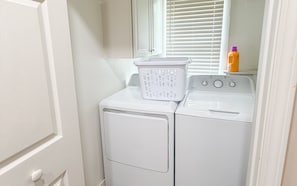 A laundry area with a washing machine and dryer, a basket, and a bottle on the dryer.