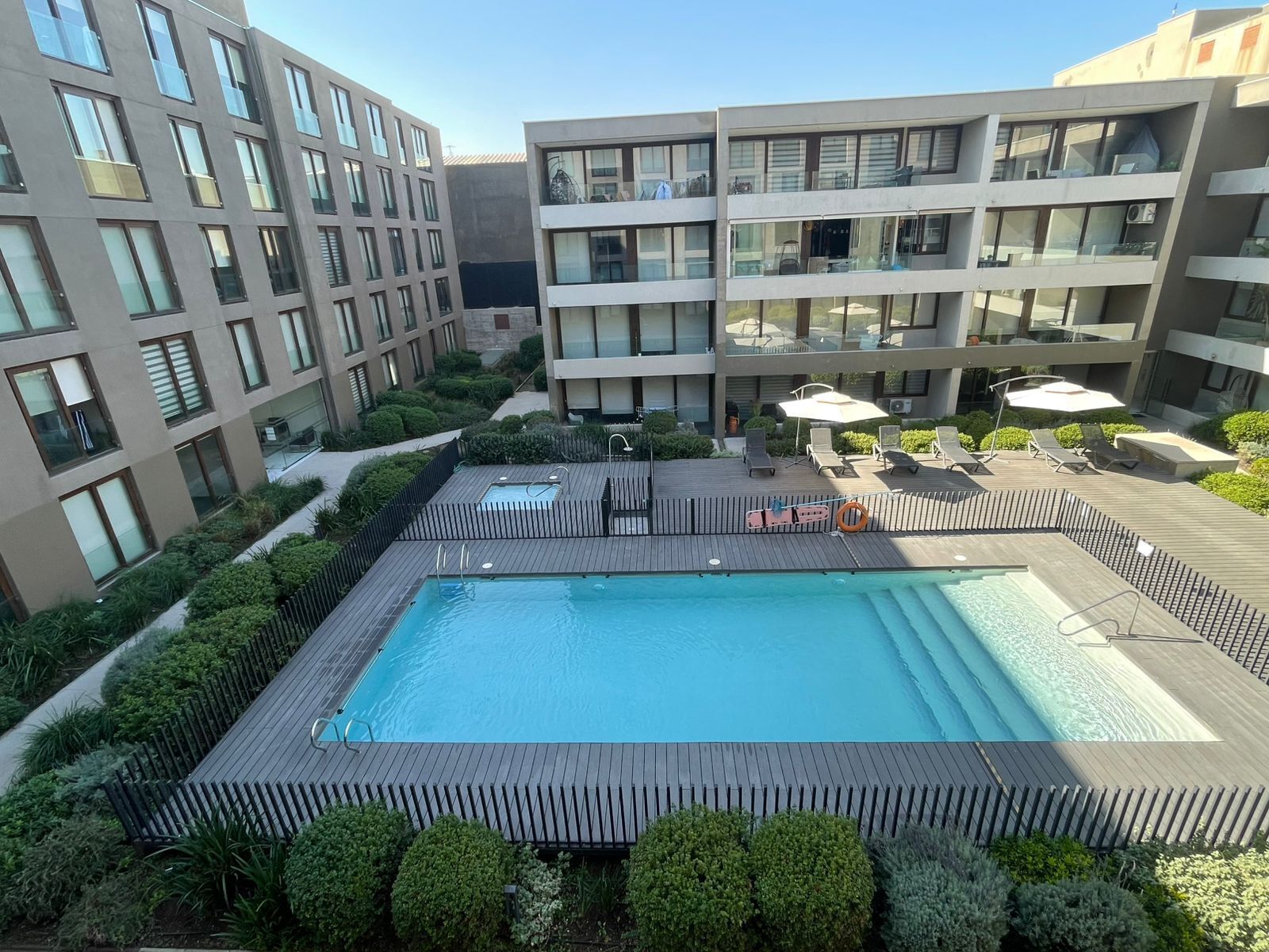 Ein Dachpool mit Holzterrasse, umgeben von Grünflächen und modernen Gebäuden.