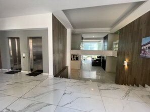 A hotel lobby with a marble floor, two elevators, a staircase, and a view of the interior space. - Quiet Studio, Best Price, and Near the Metro (Santiago)