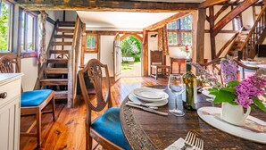 Un coin repas en bois avec une table dressée pour deux personnes, un escalier et une vue sur l’extérieur.