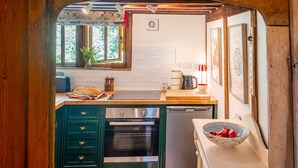 Une cuisine compacte équipée d’un four encastré, d’un évier et d’un petit lave-vaisselle.