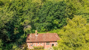 Une maison traditionnelle à toit rouge, entourée d’un feuillage verdoyant et luxuriant.