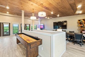 Ein Billardtisch in einem Raum mit Holzbalkendecke, einem Fernseher und einem Bücherregal.