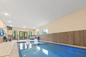 Ein Innenpool mit gefliestem Boden, einer Holzwandverkleidung und einer Sitzecke mit Stühlen und einem Tisch.