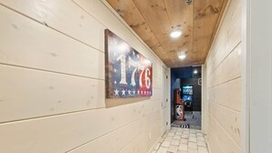 Un pasillo con paredes de madera y piso de baldosas que conduce a una sala con cancha de baloncesto.