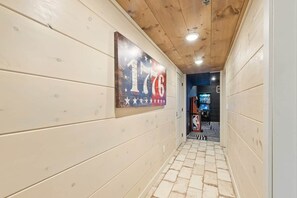Ein Korridor mit Holzwänden und Fliesenboden, der zu einem Raum mit Basketballplatz führt.