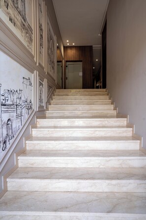 A marble staircase leading to a room with a wooden panel wall and a glass door.