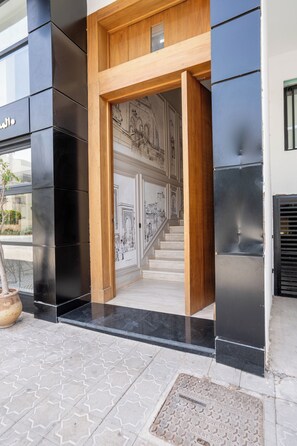 A modern building entrance with a wooden frame and a staircase leading to a second floor.