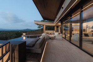 A modern outdoor living space with a pool, seating area, and a view of the mountains. - New · 180° Views – River & National Park · Infinity Pool · 3 min to the Beach (Tamarindo)
