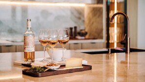 Eine Bar mit einer Weinflasche, drei Gläsern, Käse und einer Platte mit Snacks.