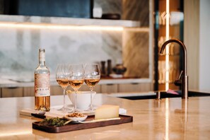 A bar area with a bottle of wine, three glasses, a cheese, and a tray with snacks. - New · 180° Views – River & National Park · Infinity Pool · 3 min to the Beach (Tamarindo)