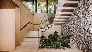 Eine moderne Treppe mit Holzvertäfelung, einer Steinwand und Blick ins Grüne.