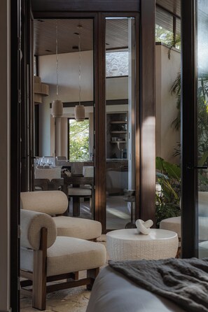 A modern interior with a seating area, a dining table, and a kitchen visible through an open door. - New · 180° Views – River & National Park · Infinity Pool · 3 min to the Beach (Tamarindo)