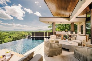 A modern outdoor pool area with a view of a mountainous landscape. - New · 180° Views – River & National Park · Infinity Pool · 3 min to the Beach (Tamarindo)