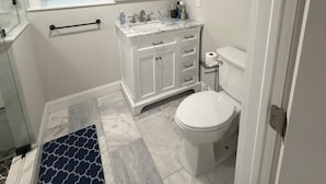 A bathroom with a toilet, sink, mirror, and a window. - Comfort, Safety, and the Beach (Clearwater)