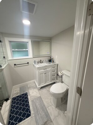 Ein Badezimmer mit Toilette, Waschbecken, Spiegel und Fenster.