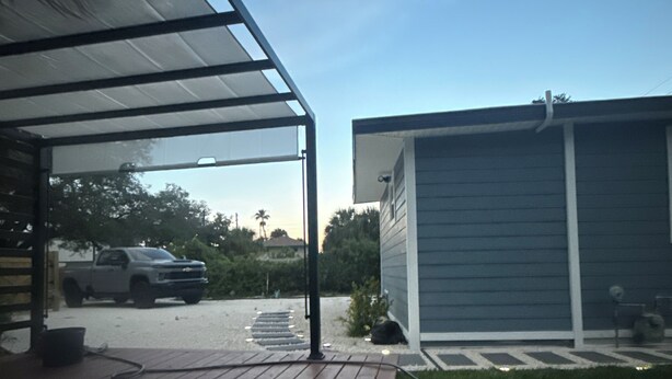 A covered outdoor area with a wooden deck, a garage, and a vehicle parked in the background. - Comfort, Safety, and the Beach (Clearwater)