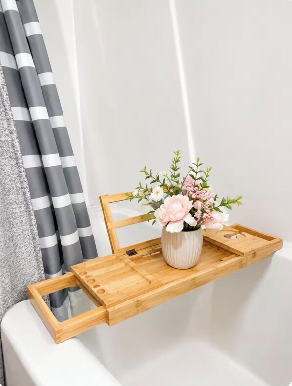 A wooden shelf with a vase of flowers in a bathroom.