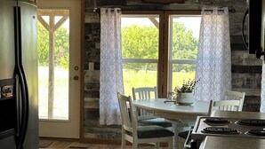 A kitchen with a refrigerator, stove, and dining area with chairs and a table.