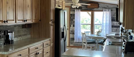 Una cocina amplia con armarios de madera, un refrigerador y un comedor con mesa y sillas.
