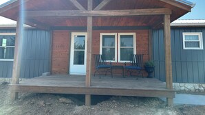 A wooden building with a porch, two windows, and a door.