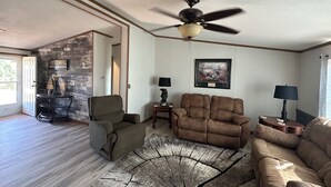 A living room with a ceiling fan, two sofas, a coffee table, and a rug.
