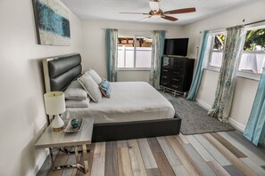 A bedroom with a bed, a nightstand, a dresser, a ceiling fan, and a window with curtains. - Beautiful 4-bedroom House With Heated Swimming Pool & Spa (Fort Lauderdale)