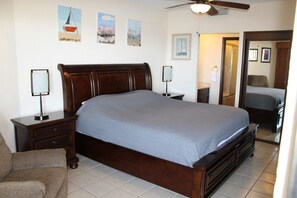 A bedroom with a large bed, two bedside tables with lamps, a chair, and artwork on the walls. - Sonoran Spa Ground Floor 109-W (Puerto Peñasco)