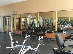 Ein Fitnessstudio mit Trainingsgeräten, Spiegeln und Gewitterracks.