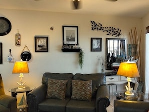 A living room with a sofa, two lamps, framed pictures, and a mirror. - Sonoran Spa Ground Floor 109-W (Puerto Peñasco)