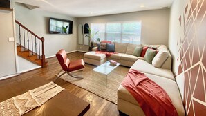 Un salon comprenant un canapé, un fauteuil, une table basse et un téléviseur fixé au mur.