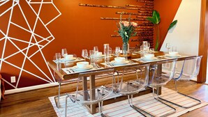 Un coin repas avec une table moderne, dressée pour quatre personnes, des chaises transparentes et un arrangement floral décoratif en guise de centre de table.