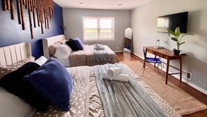 Une chambre avec deux lits, un bureau, un miroir et une télévision.