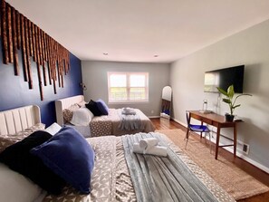 Ein Schlafzimmer mit zwei Betten, einem Schreibtisch, einem Spiegel und einem Fernseher.