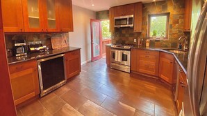 Une cuisine moderne avec des meubles en bois, des appareils électroménagers en acier inoxydable et un pare-feu en pierre.