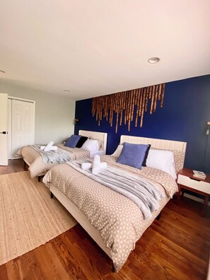 A double bed with patterned bedding, a bedside table with a book, and a wall-mounted light fixture. - Direct PATH & Bus to NYC | MetLife 20 min | Parking + Deck (Jersey City)