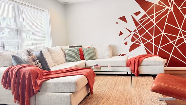 Un salon moderne avec un canapé, une table basse et une décoration murale géométrique rouge.
